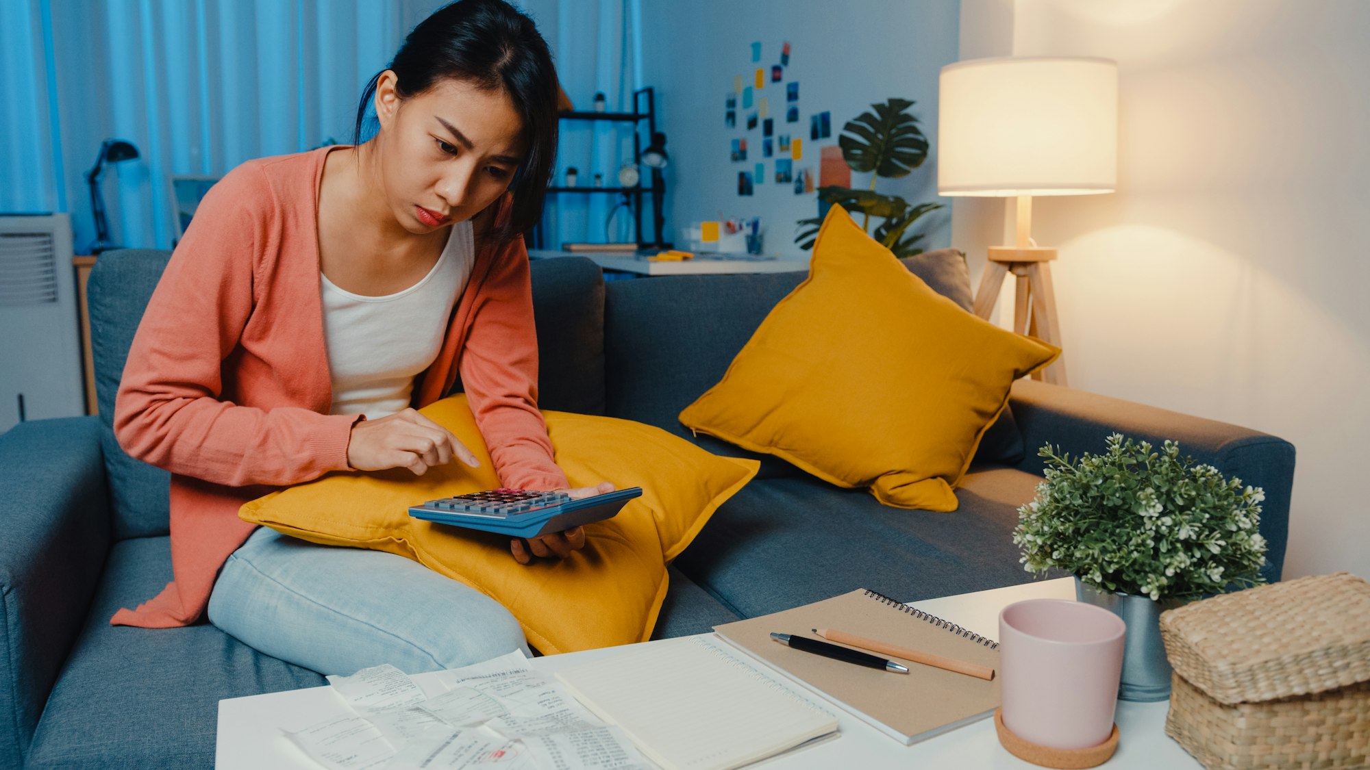 Asian lady feel stress and worried with bill and invoice credit card calculating loan on sofa.