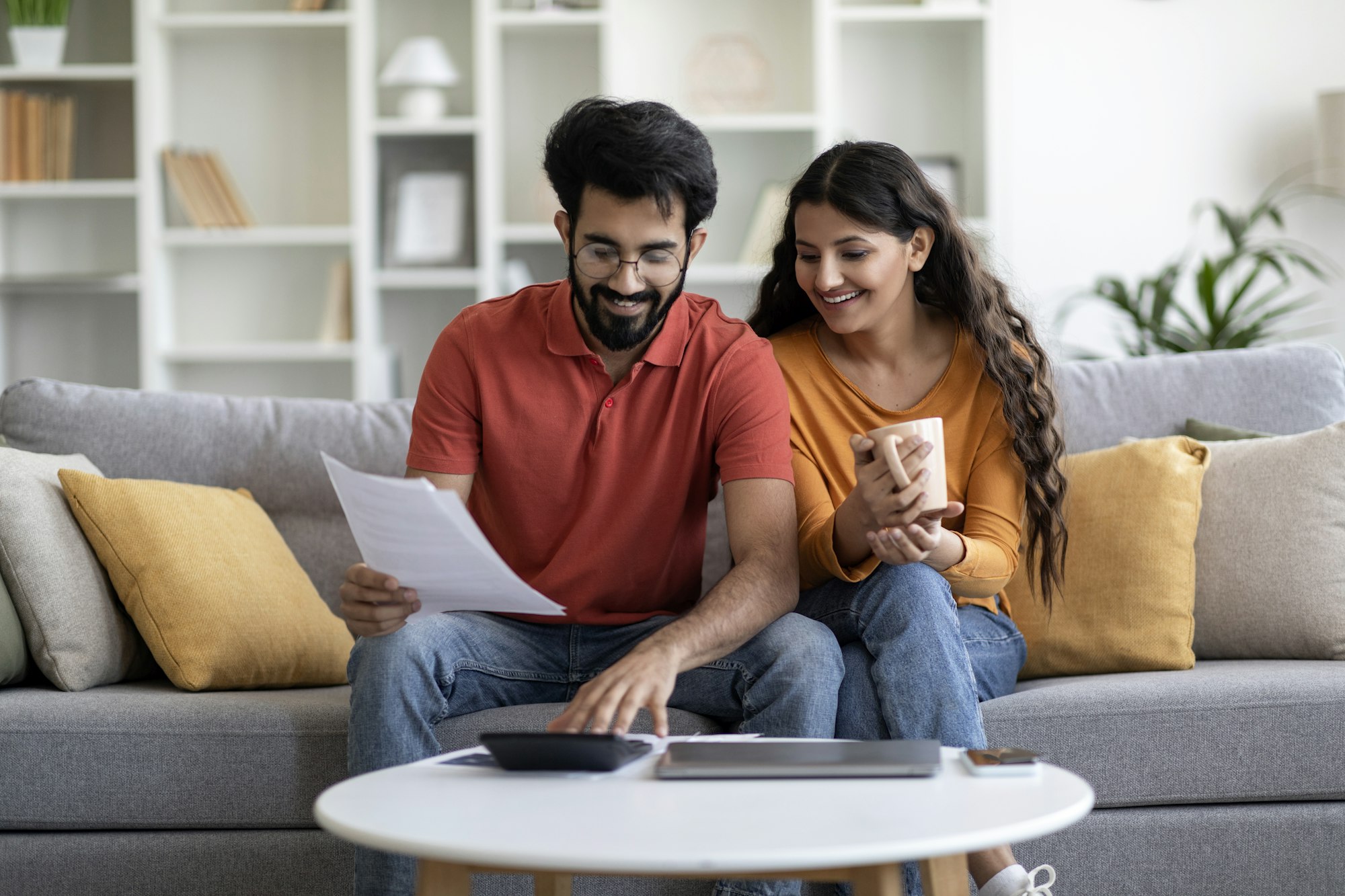 Indian Married Couple Planning Budget Together, Reading Papers And Calculating Spends